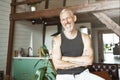 Portrait of a handsome cheerful caucasian mature man keeping arms crossed, smiling at camera while standing at his Royalty Free Stock Photo