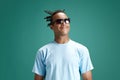 Portrait of handsome, cheerful, positive young man in sunglasses standing and smiling against green studio background Royalty Free Stock Photo