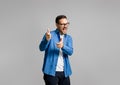 Portrait of handsome cheerful young businessman pointing at camera while posing on gray background Royalty Free Stock Photo