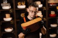 Portrait of handsome cheese sommelier with cheese gouda. Fashion worker in cheese shop. Snack tasty piece of cheese for