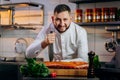 Portrait of handsome chef cooking raw meat in the kitchen. ÃÂ¡hef holds a professional kitchen knife. Concept of Cooking process Royalty Free Stock Photo