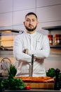 Portrait of handsome chef cooking raw meat in the kitchen. ÃÂ¡hef holds a professional kitchen knife. Concept of Cooking process Royalty Free Stock Photo