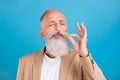 Portrait of handsome classy dreamy grey-haired man tasting good food cigarette isolated over bright blue color Royalty Free Stock Photo