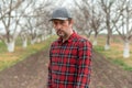 Portrait of handsome confident farmer in walnut fruit orchard looking at camera