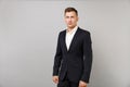 Portrait of handsome confident young business man in classic black suit white shirt standing isolated on grey wall Royalty Free Stock Photo