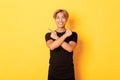 Portrait of handsome determined blond asian guy, student pointing fingers sideways, showing two variants, standing