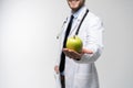 Portrait of handsome doctor in white coat looking at camera and smiling while holding an apple,  on white. Royalty Free Stock Photo