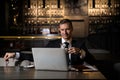 Portrait of handsome elegant caucasian businessman sitting at restaurant working on his laptop and drinking coffee