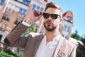 Portrait of a handsome elegant young man, model of fashion, wearing tinted sunglasses in urban background Royalty Free Stock Photo