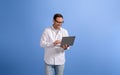 Portrait of handsome entrepreneur checking e-mails over wireless computer on blue background