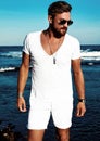 Fashion man model wearing white clothes posing on blue sea background Royalty Free Stock Photo