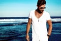 Fashion man model wearing white clothes posing on blue sea background Royalty Free Stock Photo
