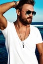 Fashion man model wearing white clothes posing on blue sea background Royalty Free Stock Photo