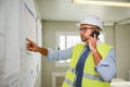 Portrait of handsome foreman construction worker man on industrial building industry construction site studying blueprint indoo