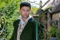 Portrait of handsome gentleman dressed in vintage costume standing next to iron gate, looking pensive