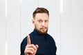 Portrait of handsome guy with beard showing pointing finger up. Businessman idea