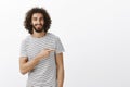 Portrait of handsome guy with charming smile and curly hair in casual clothes, pointing right and smiling with assured Royalty Free Stock Photo