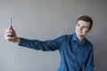 Portrait of a handsome guy looking into the camera with a phone in his hand. The guy makes self photo. In a green shirt. Brunette Royalty Free Stock Photo