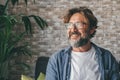 Portrait of handsome happy mature man looking away and smiling in the living room of modern apartment. Thoughtful guy with Royalty Free Stock Photo