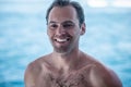 Portrait of handsome happy, sexy man with white teeth smile and wet body, surfer and blue ocean