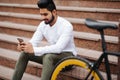 Portrait of handsome indian young man with mobile phone and fixed gear bicycle in the city Royalty Free Stock Photo