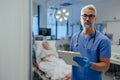 Portrait of handsome male doctor, patient in hospital bed behind. ER doctor examining senior patient, reading her Royalty Free Stock Photo