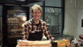 Portrait of the handsome man baker in plaid shirt and apron smiling to the camera and posing in the bakery shop. Close