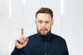 Portrait of handsome man with beard showing pointing finger up. Businessman idea
