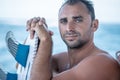 Portrait of handsome man with blue eyes, surfer holding surf board with blue fins and blue ocean Royalty Free Stock Photo