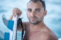 Portrait of handsome man with blue eyes, surfer holding surf board with blue fins and blue ocean Royalty Free Stock Photo