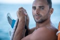 Portrait of handsome man with blue eyes, surfer holding surf board with blue fins and blue ocean Royalty Free Stock Photo