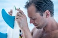 Portrait of handsome man with blue eyes, surfer holding surf board with blue fins and blue ocean Royalty Free Stock Photo