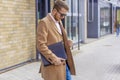 Portrait of a handsome man, businessman, scientist or teacher. He walks along a modern city street with a folder of documents and Royalty Free Stock Photo