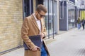 Portrait of a handsome man, businessman, scientist or teacher. He walks along a modern city street with a folder of documents Royalty Free Stock Photo