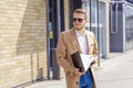 Portrait of a handsome man, businessman, scientist or teacher. He walks along a modern city street with a folder of documents Royalty Free Stock Photo