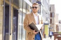 Portrait of a handsome man, businessman, scientist or teacher. He walks along a modern city street with a folder of documents Royalty Free Stock Photo