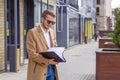Portrait of a handsome man, businessman, scientist or teacher. He walks along a modern city street with a folder of documents Royalty Free Stock Photo