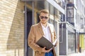 Portrait of a handsome man, businessman, scientist or teacher. He walks along a modern city street with a folder of documents and Royalty Free Stock Photo