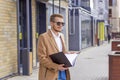 Portrait of a handsome man, businessman, scientist or teacher. He walks along a modern city street with a folder of documents Royalty Free Stock Photo