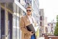 Portrait of a handsome man, businessman, scientist or teacher. He walks along a modern city street with a folder of documents Royalty Free Stock Photo