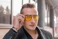 Portrait of a handsome man of European appearance businessman adjusting sunglasses with his hand, close-up on the outdoor of the Royalty Free Stock Photo