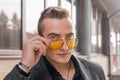 Portrait of a handsome man of European appearance businessman adjusting sunglasses with his hand, close-up on the outdoor of the Royalty Free Stock Photo