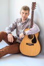 Portrait of handsome man with guitar siting on floor Royalty Free Stock Photo