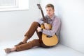 Portrait of handsome man with guitar siting on floor Royalty Free Stock Photo