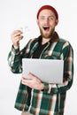 Portrait of handsome man holding silver laptop and credit card, while standing isolated over white background Royalty Free Stock Photo