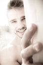 Portrait of handsome man lit by sunshine through window peeking out from behind curtain Royalty Free Stock Photo