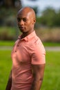 Portrait handsome man looking over shoulder towards camera. ADult bald male model posing in a pink polo style shirt Royalty Free Stock Photo