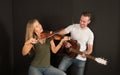 Portrait of a handsome man musician plays the guitar, a beautiful woman musician plays the violin Royalty Free Stock Photo