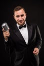 Portrait of handsome man sing on microphone on black background Royalty Free Stock Photo