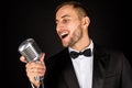 Portrait of handsome man sing on microphone on black background. Royalty Free Stock Photo
